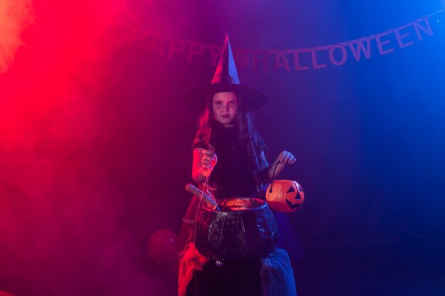 Little witch child cooking potion in the cauldron on halloween