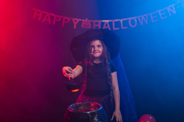 Little witch child cooking potion in the cauldron on halloween