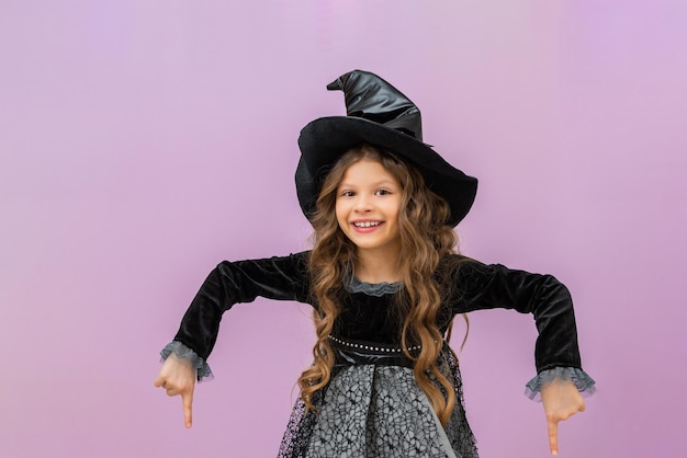 The little witch points down at the advertisement The carnival costume of the enchantress