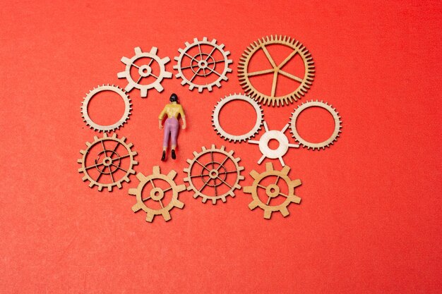 Photo little woman figurine and wooden gear wheels in view