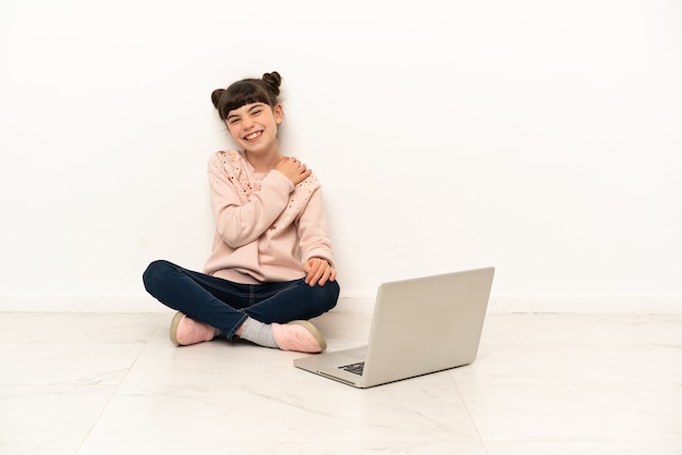 Little woman with a laptop sitting on the floor laughing