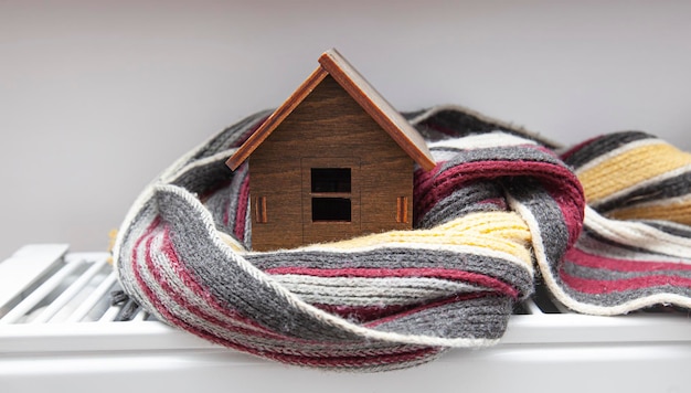 Photo the little wooden house wrapped in the scarf lying on the radiator in the house