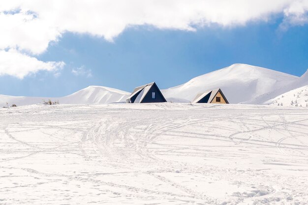 Little wooden rural village houses buildings with snow ice in high mountains in sunny cold frosty day Winter beautiful scenic nature panorama on ski resortUkrainian Carpathians landscape