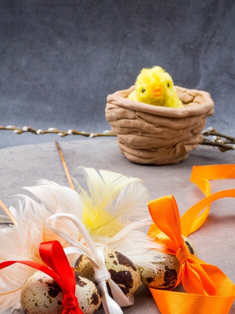 Little yellow toy chicken and Easter eggs tied in a bows with ribbon copy space