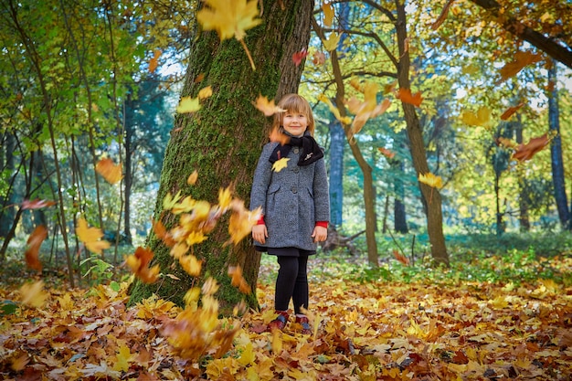 小さな女の子は紅葉で遊ぶ