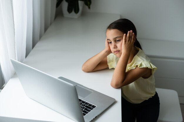 Litttle girl looking at laptop screen with expression of surprised and excitement. Smart, smilling little girl taking notes . Communication in business concept.