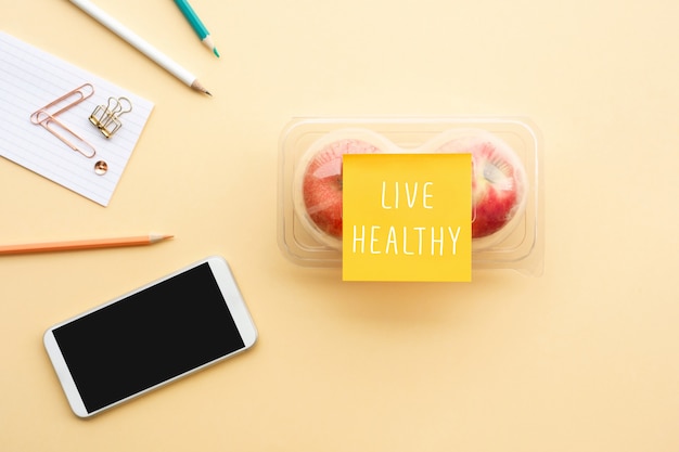 机の上のパッケージにテキストノートと赤いリンゴで健康的な概念を生きる