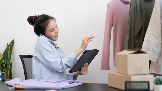 Live shopping concept een vrouwelijke dealer die een tabletpotlood gebruikt dat op de tablet veegt om de bestellingen van de dag te controleren.