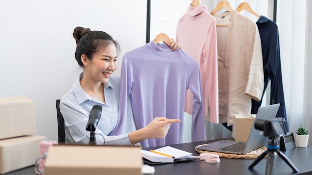 Live shopping concept a female seller talking to online customers showing a product through a sale live in front of a camera.