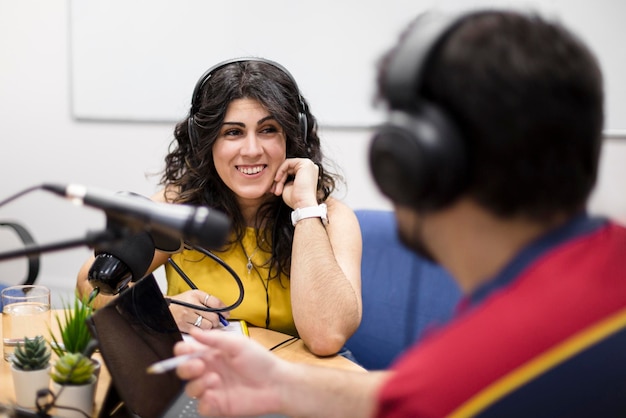 Live-uitzending van een radioprogramma of podcast Glimlachende jonge blanke vrouw aan het chatten met haar partner