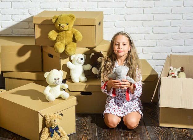 Photo live the uptown urban lifestyle. purchase of new habitation. happy little girl with toy. happy child cardboard box. cardboard boxes - moving to new house. playing into new home. new apartment.