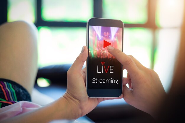 Concetto di streaming video in diretta. mani femminili che tengono il telefono cellulare