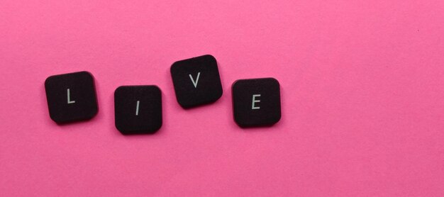 Live word made of black cubes on pink background top view