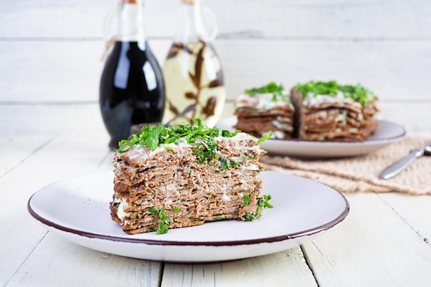 Liver cake on wooden background Sliced layered liver cake with mayonnaise