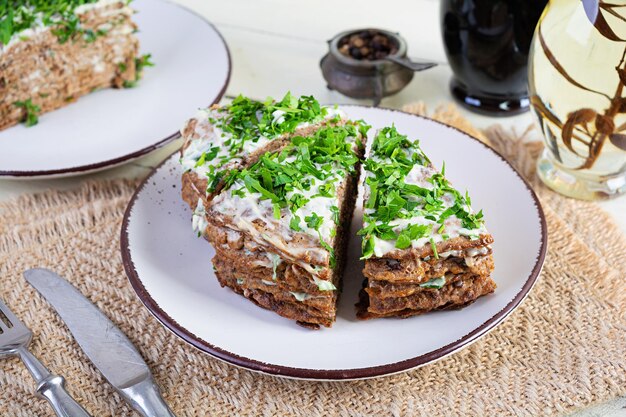 Liver cake on wooden background Sliced layered liver cake with mayonnaise