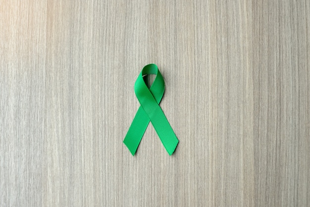 Liver Cancer Awareness, green Ribbon on wooden background 