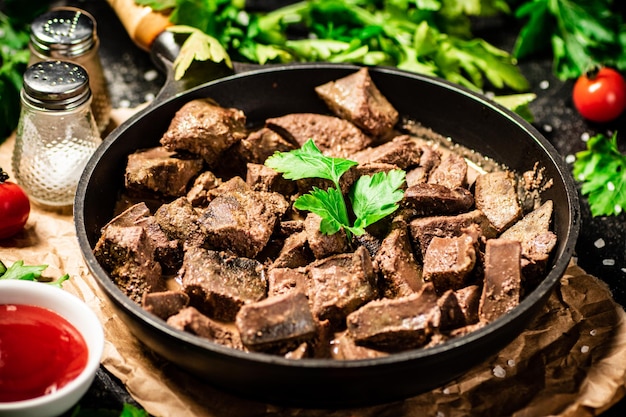 Liver cooked in a frying pan with cherry tomatoes and herbs