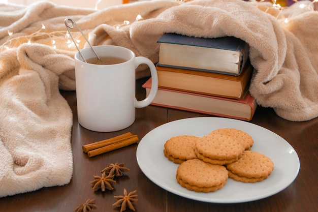 Dettagli del soggiorno in inverno primo piano di una tazza bianca con un infuso su un tavolo di legno con anice e cannella e una coperta color crema concetto di comfort domestico e vita interiore