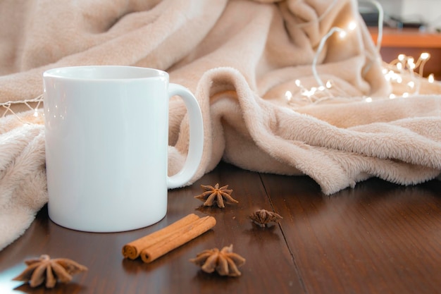 Living room details in winter Closeup of a white cup with an infusion on a wooden table with anise and cinnamon and a cream colored blanket Concept of home comfort and inner life