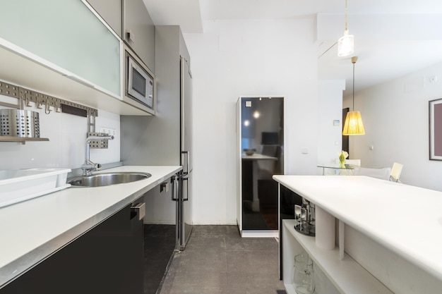 Living room of a furnished apartment with an open kitchen with furniture in gray and black tones with a white countertop and island of the same color