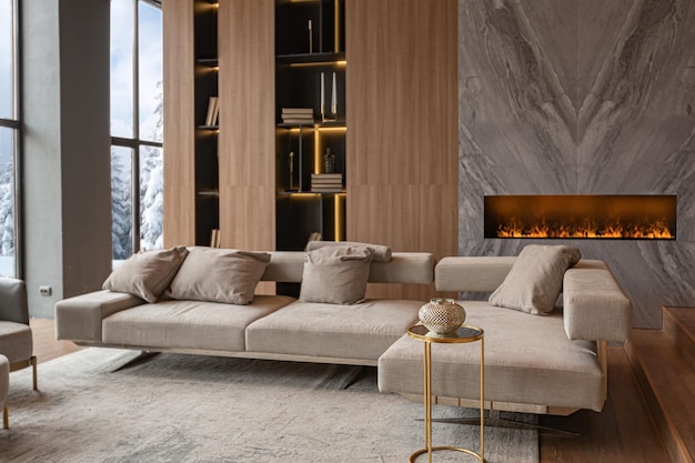 Living room marble wall fireplace and stylish bookcase in chic expensive interior of luxury country house with a modern design with wood and led light gray furniture with gold elements