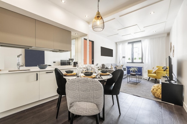 Foto soggiorno di una casa vacanza con cucina aperta sul soggiorno tavolo da pranzo in marmo bianco sedie imbottite e grandi finestre con tende