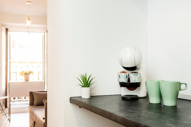 Living room with a black countertop with a pod coffee machine and two green porcelain pitchers