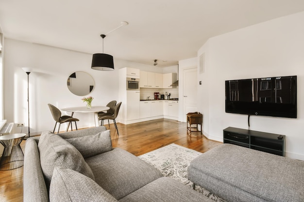 A living room with couches and a flat screen tv on the wall in the center of the room is a dining table