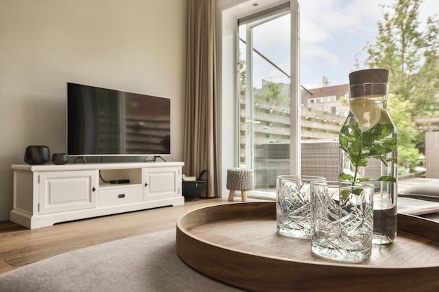 a living room with a glass vase on the coffee table and a television set in the window is behind it