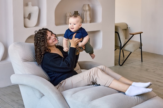 Living room with happy woman and baby who sit on sofa