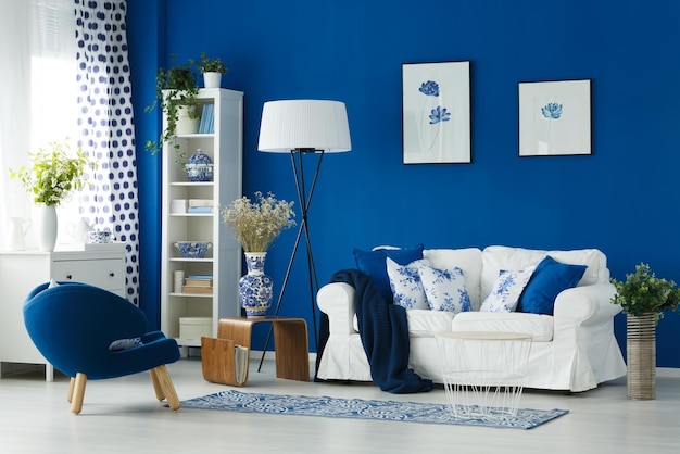 A living room with a white couch and a white sofa with blue pillows and a white sofa.