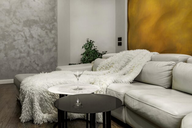 Living room with white walls and a huge white sofa a black glossy wardrobe with a large yellow 3D panel on the wall