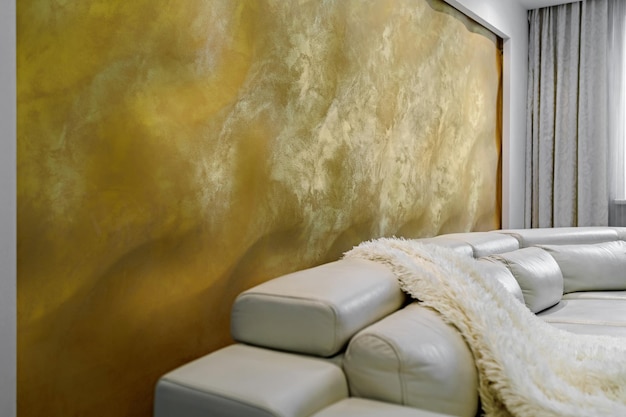 Гостиная с белыми стенами и огромным белым диваном, черный глянцевый шкаф с большой желтой 3D-панелью на стене