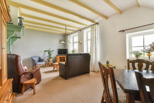 A living room with wood beams on the ceiling and chairs in the room is very clean ready for guests