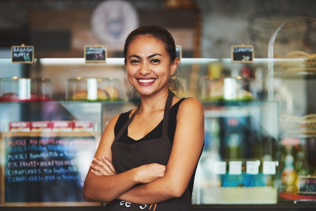 Living that cafe life Portrait of a young barista posing with her arms crossed in a coffee shot