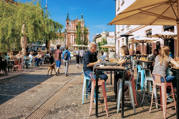 Ljubljana, Slovenië - 27 April 2018: Mensen op stoep straat café in de buurt van Franciscaanse kerk van de aankondiging in het historische centrum van Ljubljana, Slovenië