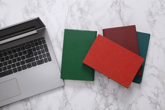 Photo llaptop and stack of books on marble surface education concept top view