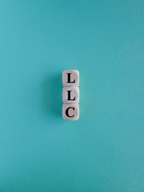 LLC Limited Liability Company acroniem op houten kubussen op een blauwe achtergrond