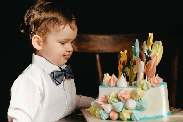 Llittle ragazzo accanto a una torta per il suo compleanno