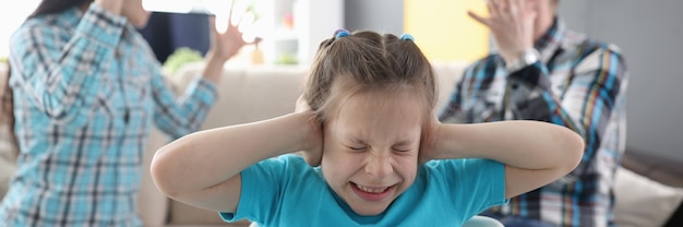 Photo llittle girl in fear closes her ears so as not to hear her parents swear