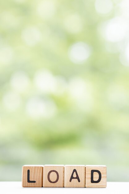 Load word is written on wooden cubes on a green summer background Closeup of wooden elements