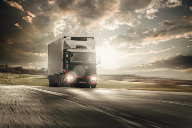Foto camion carico che viaggia veloce sull'autostrada senza pedaggio con luce nel sole splendente e un cielo cupo