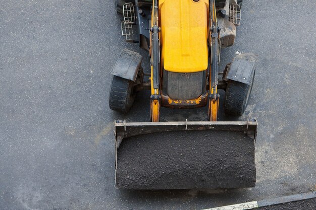 写真 シャベルで地面を備えたローダー。自治体による道路または芝生の修理。トラクター作業工事現場。上面図。