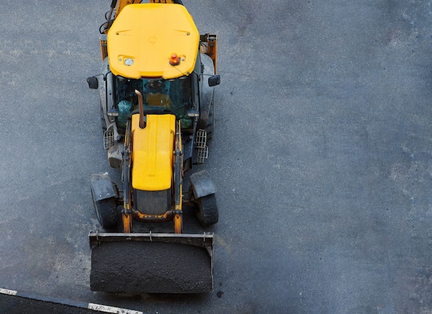 Loader with ground in shovels. Road or lawn repair by municipality. Tractor working construction site. Top view.