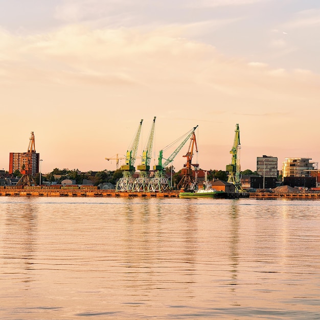 Loading cranes and oil tanks in Baltic sea in Port of Klaipeda, Lithuania. At sunset