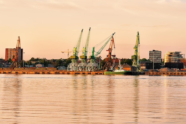 リトアニアのクライペダ港のバルト海でクレーンと船を積み込みます。日没時に