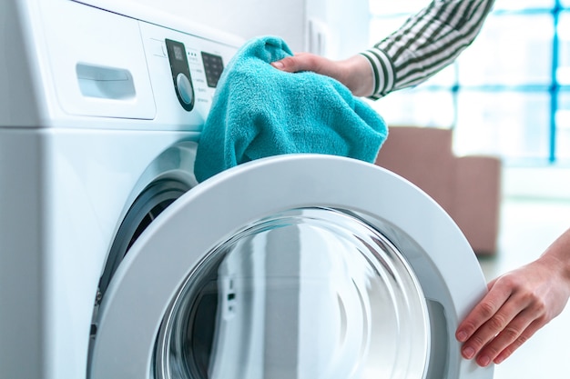 Loading towel, clothes and linen in washing machine. Doing laundry at home. Household chores and housekeeping