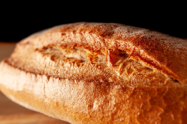 暖かい地殻で焼いた暗い背景のパンのボード上のパンの塊