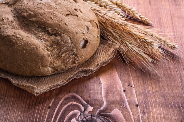 Pagnotta di pane e orecchie di rie su tavola vintage