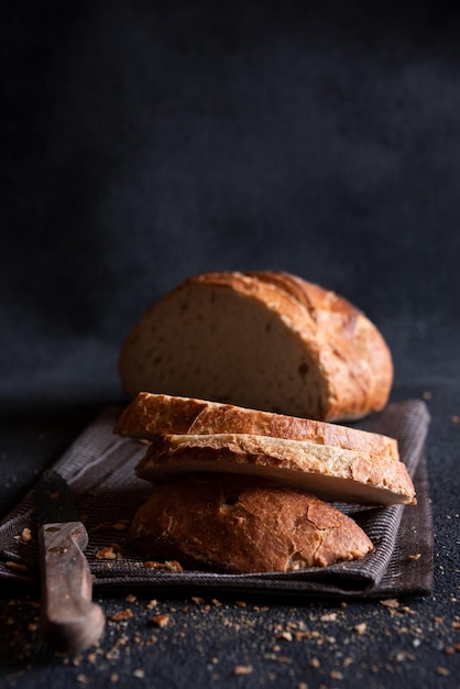 Loaf of bread freshly baked and cut on dark background